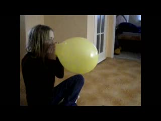 cute girl blows up a yellow balloon until it pops